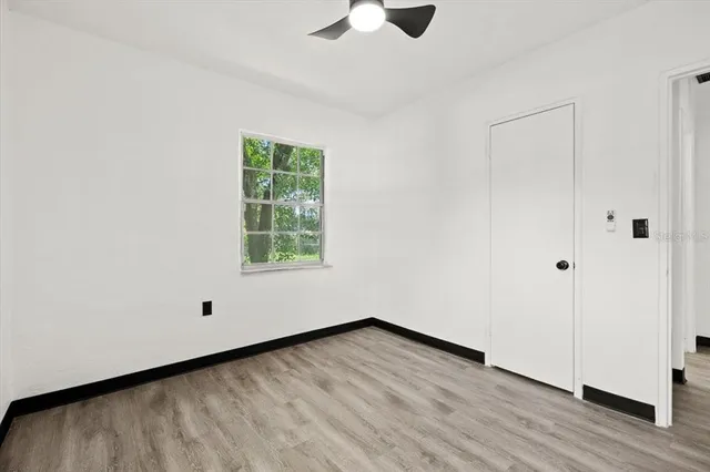 a view of an empty room with wooden floor and a window