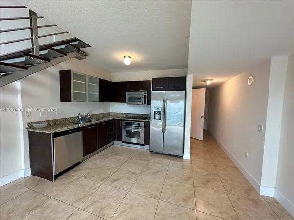 a large kitchen with stainless steel appliances kitchen island granite countertop a refrigerator and a sink