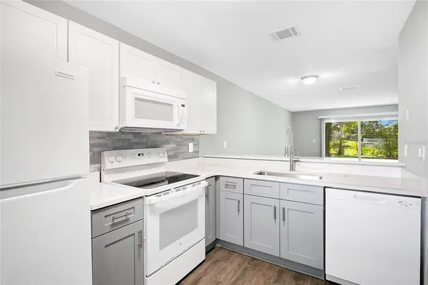 a kitchen with white cabinets appliances and a window