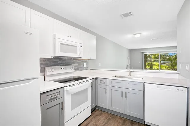a kitchen with white cabinets appliances and a window