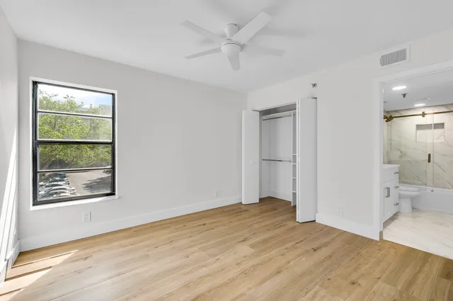 a view of empty room with wooden floor and fan