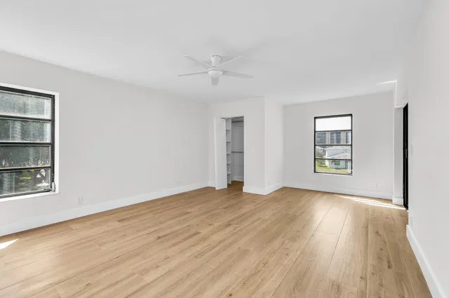 a view of an empty room with a window and wooden floor
