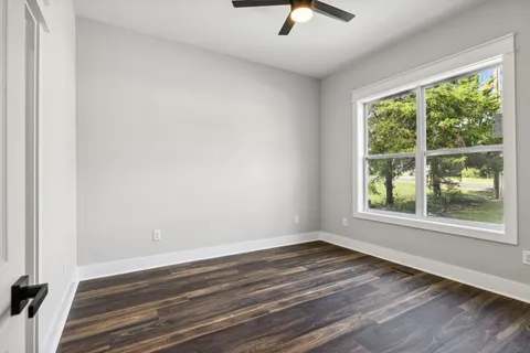 an empty room with wooden floor and windows