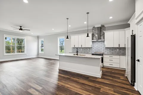 a kitchen with stainless steel appliances granite countertop a sink a refrigerator a center island and wooden floor