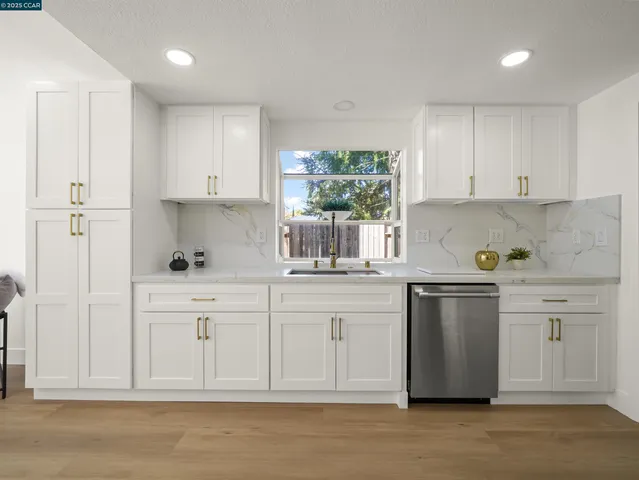 a kitchen with white cabinets and sink