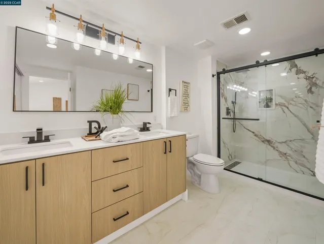 a bathroom with a double vanity sink toilet and shower