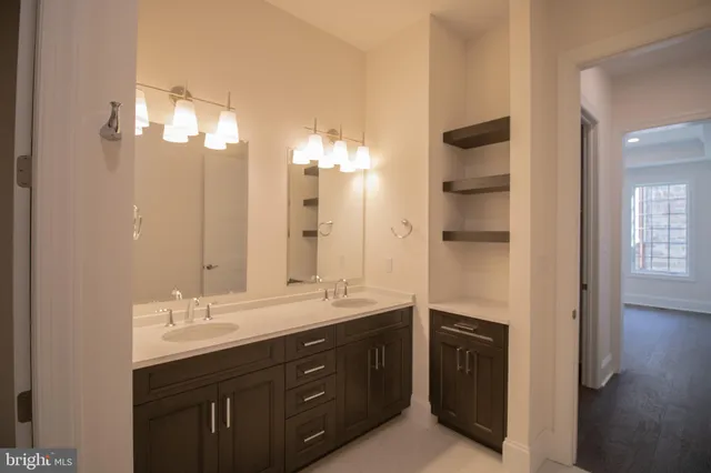 a spacious bathroom with a double vanity sink a large mirror and a shower