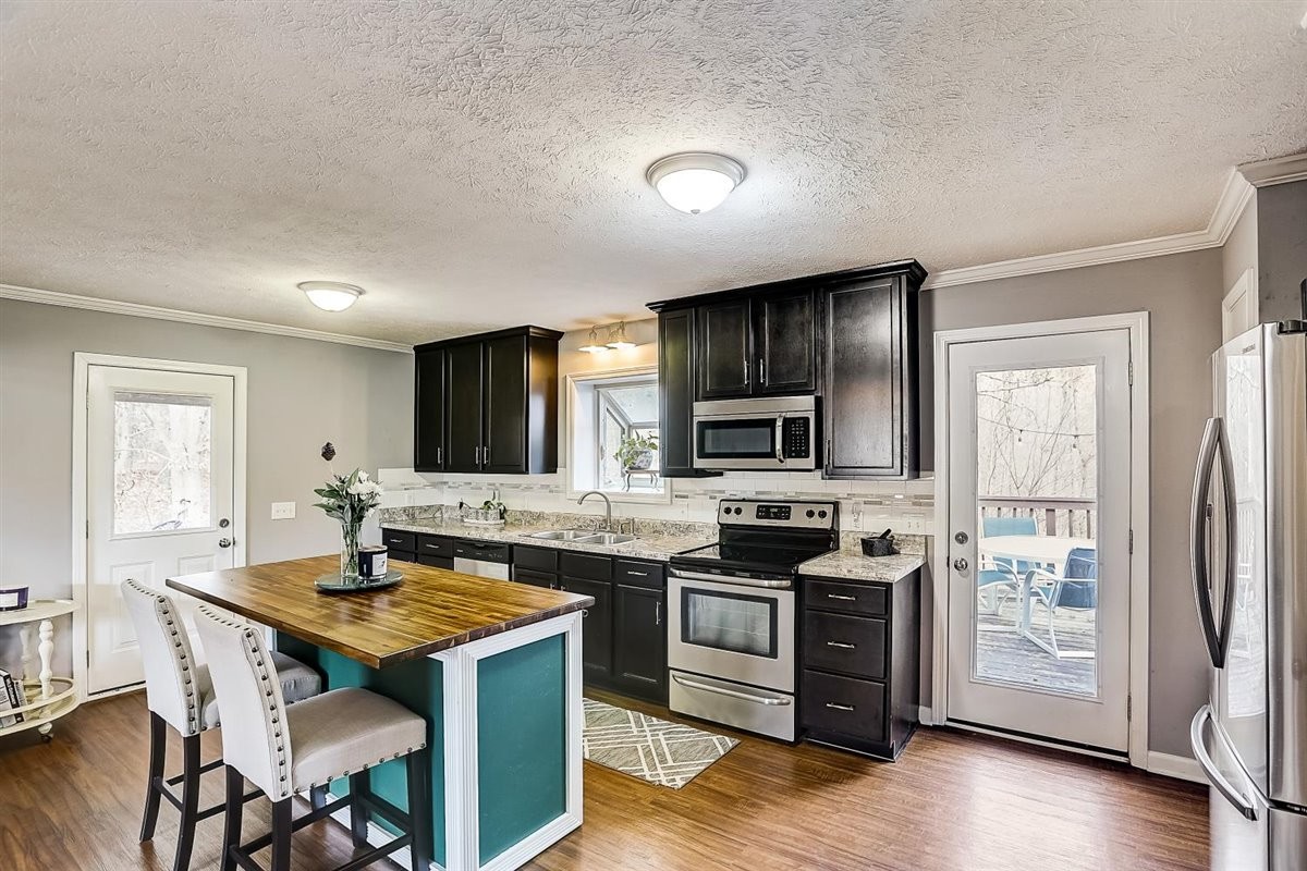 2087 River Road Clarksville, TN 37040 - Photo 13 of 33 a kitchen with stainless steel appliances granite countertop a stove top oven a sink dishwasher a dining table and chairs with wooden floor