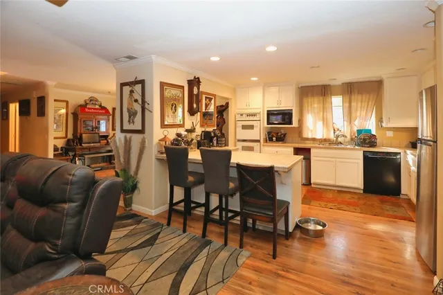 a living room with stainless steel appliances lots of furniture and kitchen view