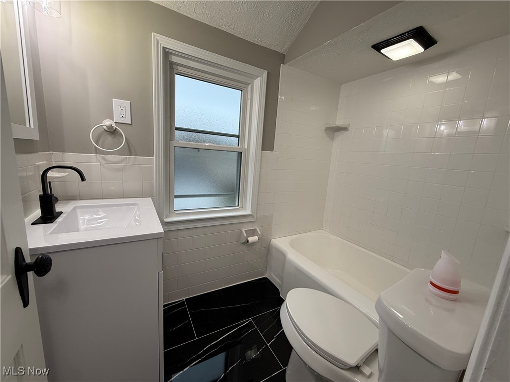 6807 Gerald Avenue Parma, OH 44129 - Photo 12 of 25 Bathroom featuring toilet, a textured ceiling, tile walls, and vanity