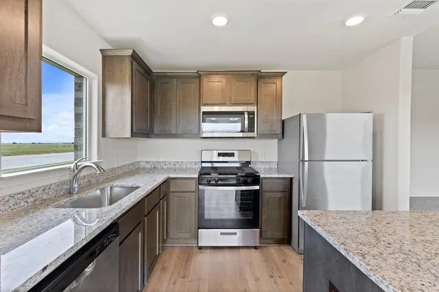 a kitchen with stainless steel appliances granite countertop a sink stove and refrigerator