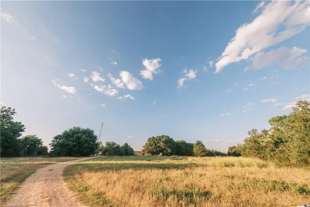 an aerial view of a residential houses with outdoor space and trees all around