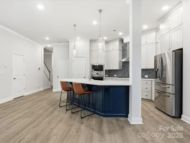 a kitchen with stainless steel appliances granite countertop a refrigerator a sink a stove a dining table and chairs