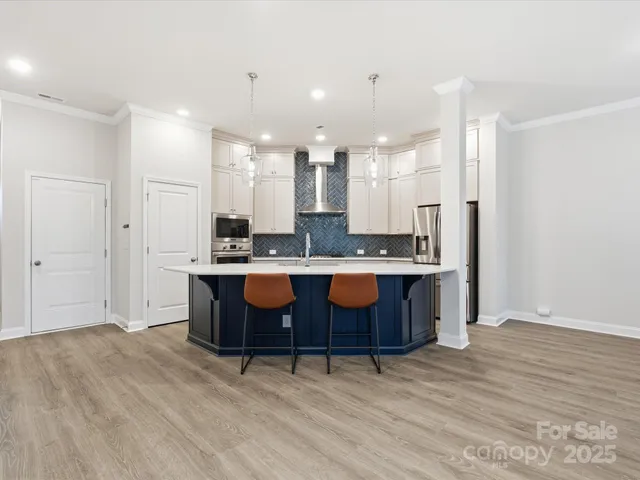 a large kitchen with a large counter top a sink stainless steel appliances and cabinets