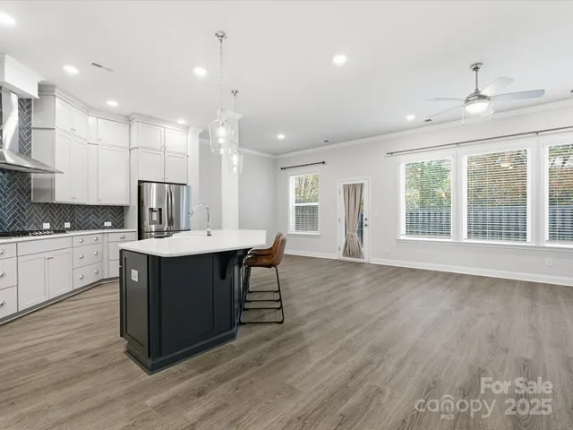 a kitchen with kitchen island granite countertop a sink cabinets and wooden floor