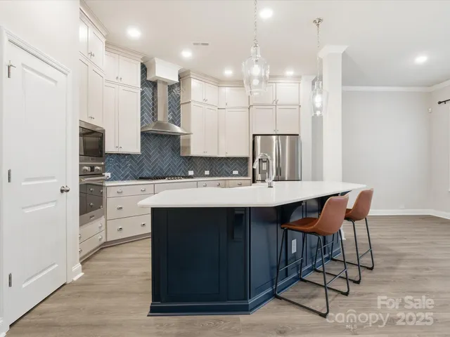 a kitchen with stainless steel appliances granite countertop a table chairs sink and cabinets