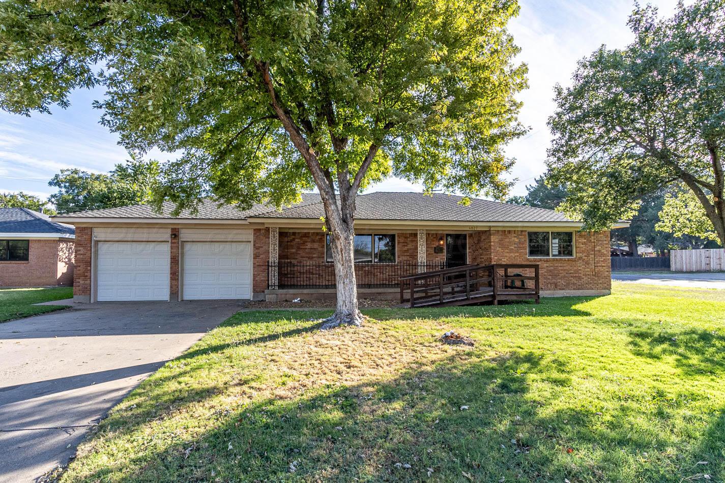 a view of a house with a yard and large tree