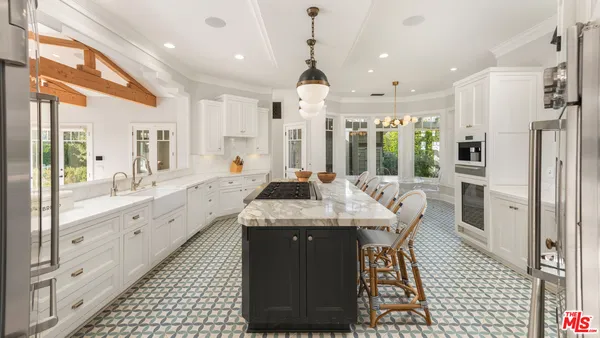 a large kitchen with granite countertop a stove a sink dishwasher and a refrigerator with wooden floor