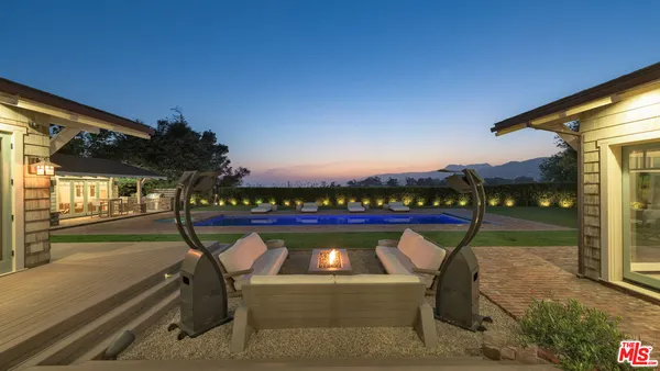 a view of a pool with a yard in front of it