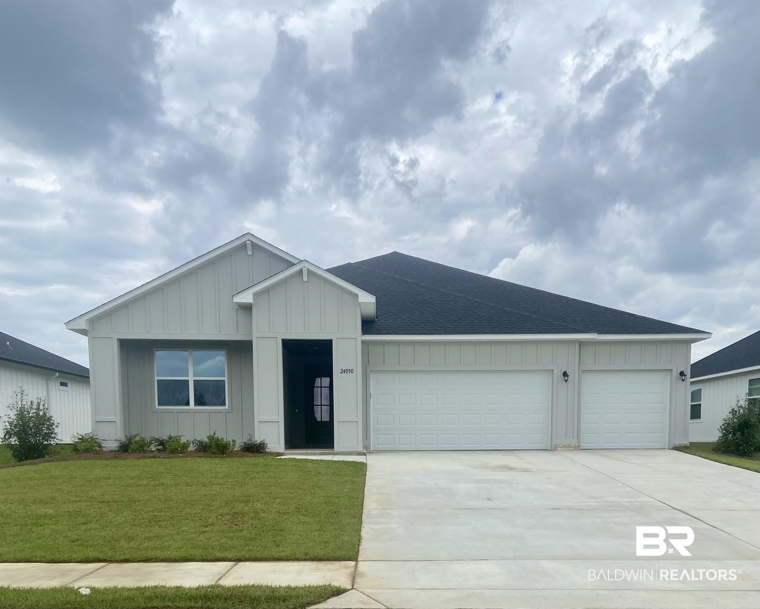 24050 Shadowridge Drive Daphne, AL 36526 - Photo 1 of 2 Ranch-style home featuring board and batten siding, a front yard, driveway, an attached garage, and a shingled roof