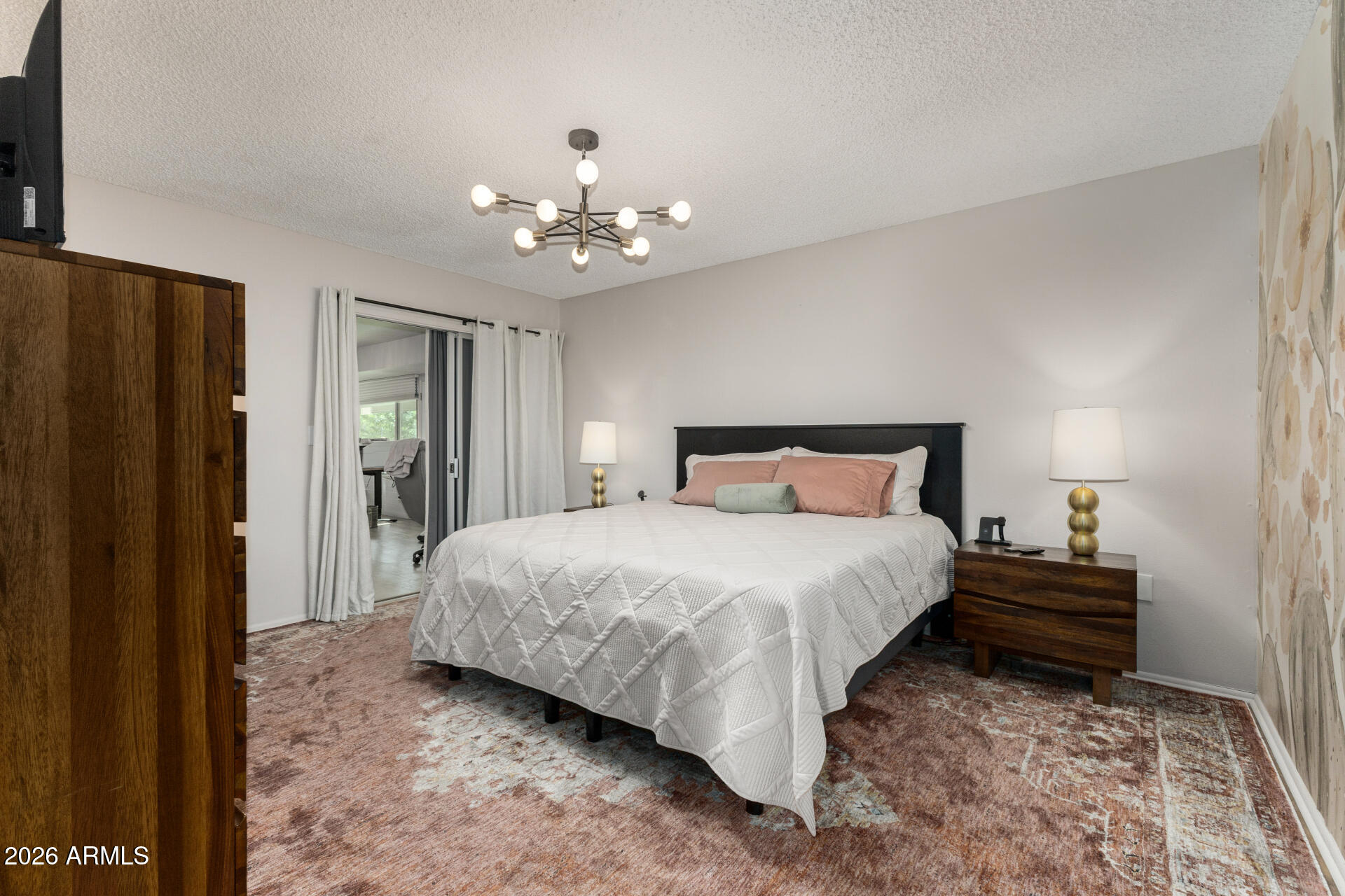 9933 West Mountain View Road Sun City, AZ 85351 - Photo 18 of 24 a spacious bedroom with a bed and a chandelier