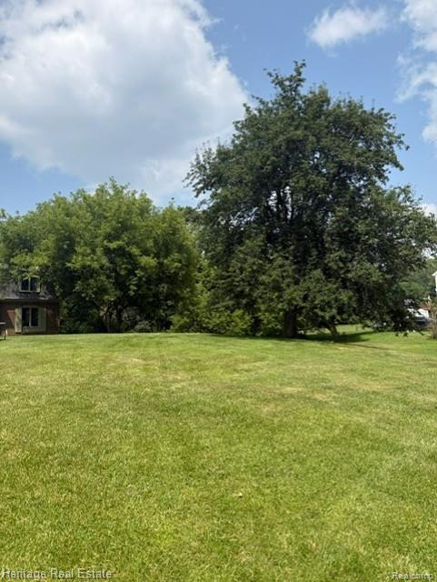 445 Mack Road Leonard, MI 48367 - Photo 41 of 41 Expansive green lawn with mature trees and a partial view of a brick exterior