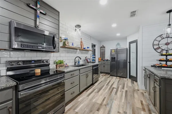a kitchen with stainless steel appliances a stove a sink and a microwave