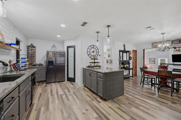 a kitchen with stainless steel appliances granite countertop a lot of cabinets and wooden floor