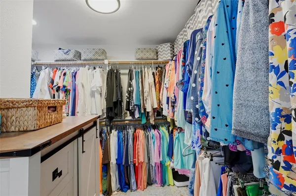 a view of walk in closet with clothes and shoes