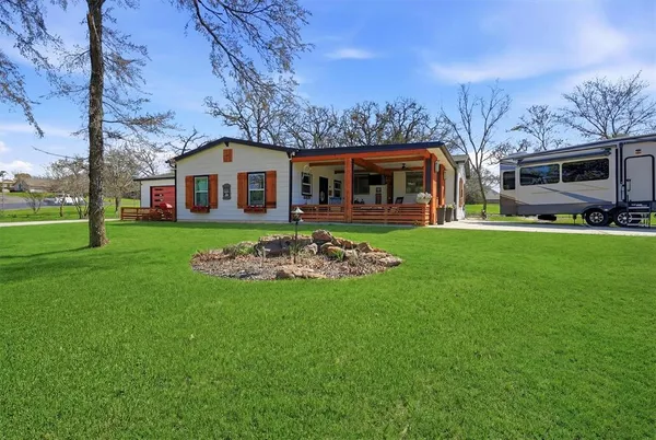 a front view of a house with a garden and trees