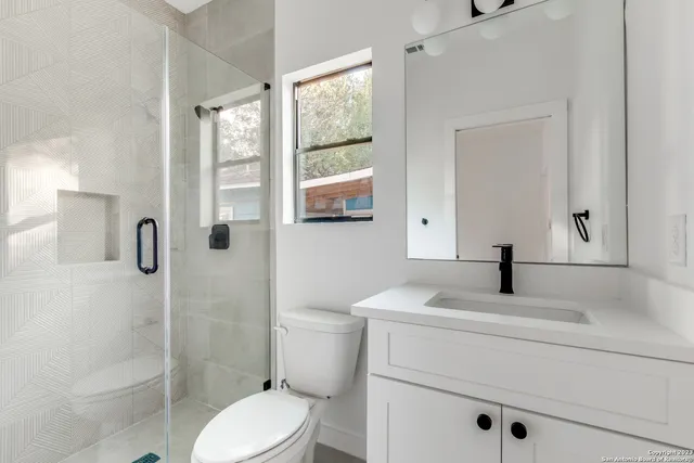 a bathroom with a granite countertop sink toilet a mirror and shower