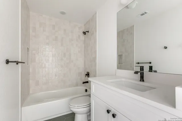 a bathroom with a sink a toilet a mirror a bathtub and shower