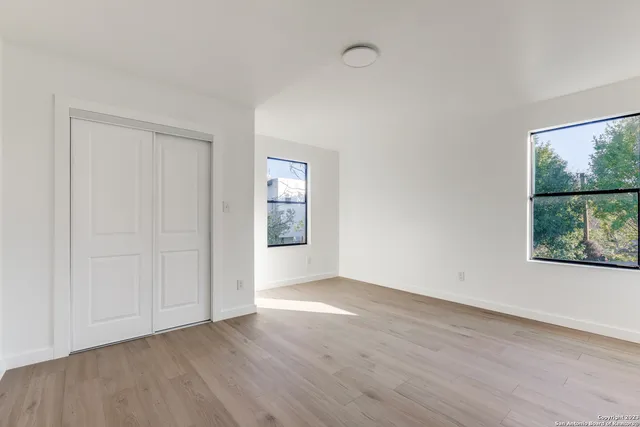 an empty room with wooden floor and windows