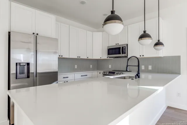 a kitchen with stainless steel appliances a stove a sink a microwave a refrigerator and cabinets