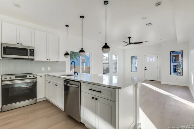 a kitchen with stainless steel appliances granite countertop a sink a stove and a wooden floors