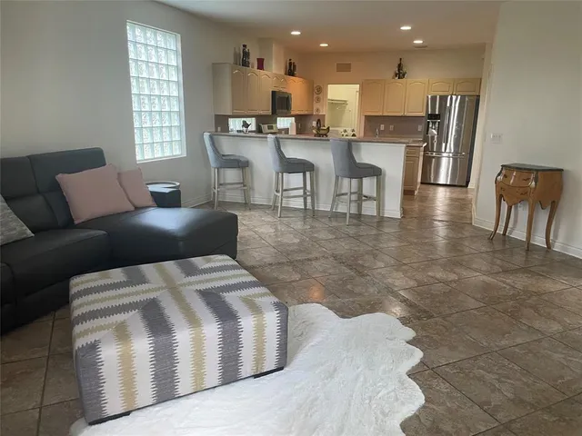 a living room with stainless steel appliances kitchen island granite countertop a table chairs and a view of living room