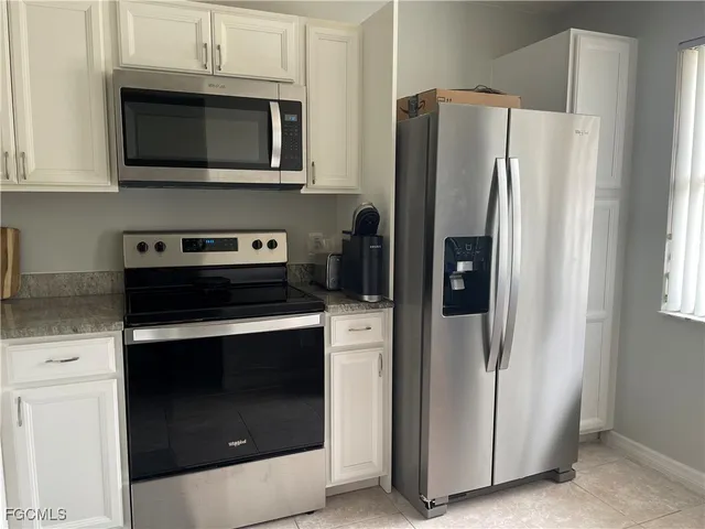 a kitchen with stainless steel appliances white cabinets white stove and a refrigerator