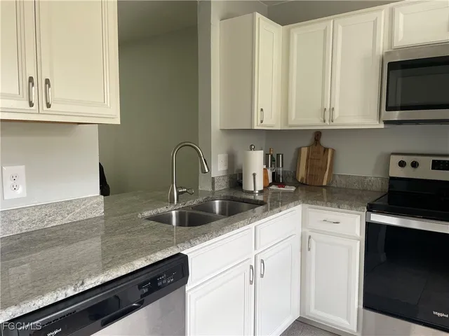 a kitchen with granite countertop white cabinets and a sink