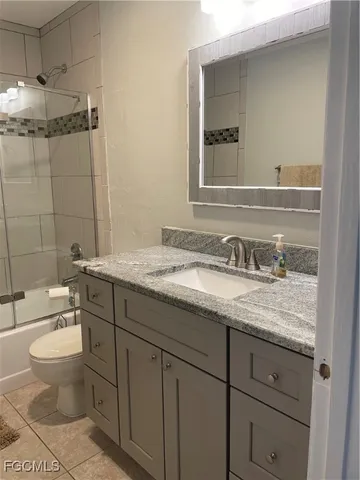 a bathroom with a granite countertop sink toilet and mirror