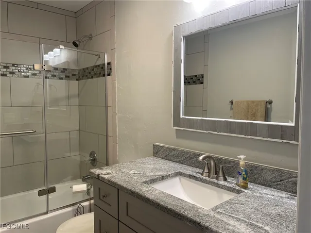 a bathroom with a granite countertop sink a mirror and shower