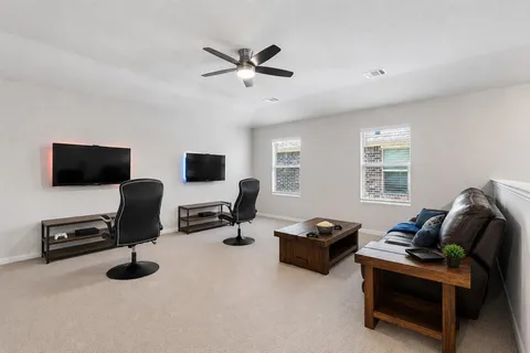 a living room with furniture gym equipment and a ceiling fan