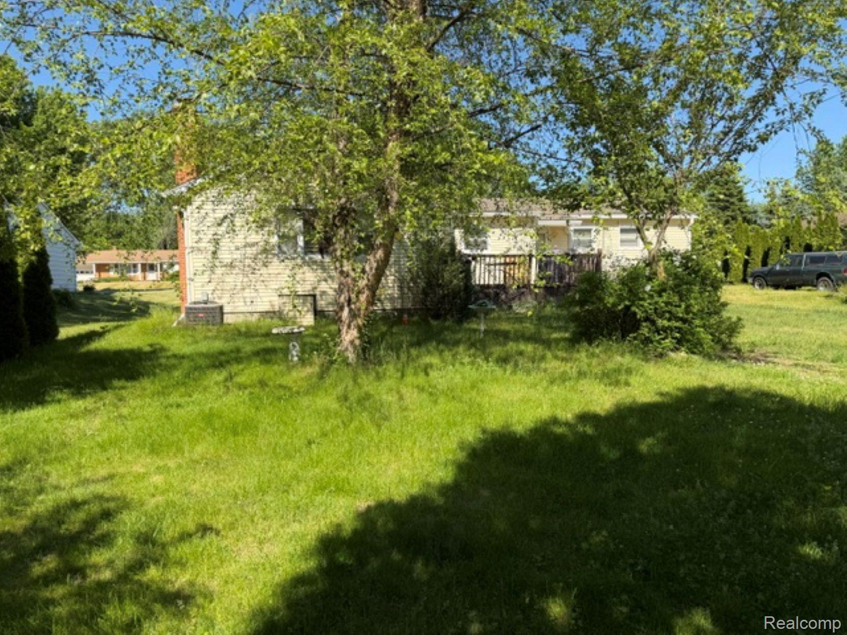 53151 Fairchild Road Macomb, MI 48042 - Photo 4 of 22 Expansive green lawn with mature trees and a rear deck
