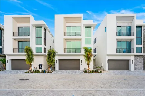a view of a house with potted plants and a large tree
