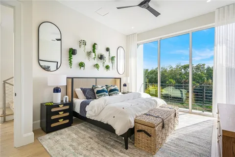 a bedroom with a bed a table and large windows