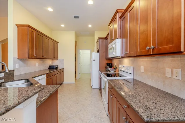a kitchen with stainless steel appliances granite countertop wooden cabinets a stove and a sink