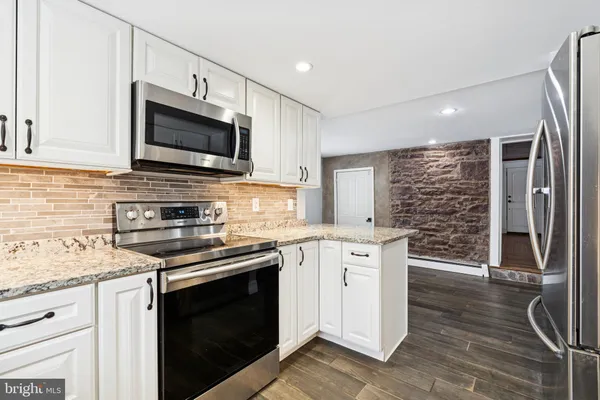 a kitchen with stainless steel appliances granite countertop a stove microwave and cabinets