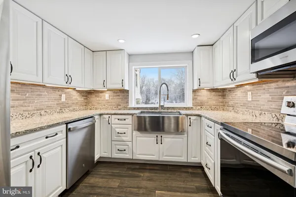 a kitchen with granite countertop white cabinets white stainless steel appliances and sink