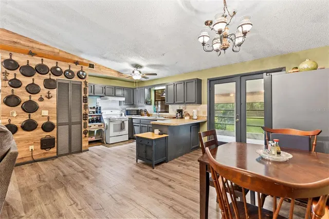 a dining room with stainless steel appliances kitchen island granite countertop a table chairs and a chandelier
