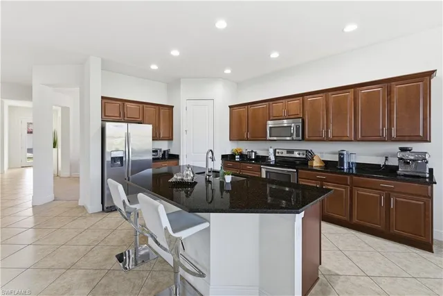a kitchen with stainless steel appliances granite countertop a stove top oven a sink a refrigerator and cabinets
