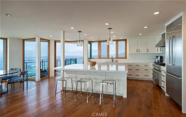 a kitchen with stainless steel appliances granite countertop a stove refrigerator dining table and chairs